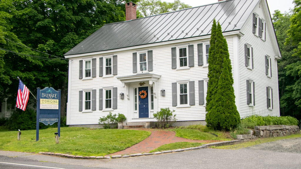 White building with black shutters and metal roof. 